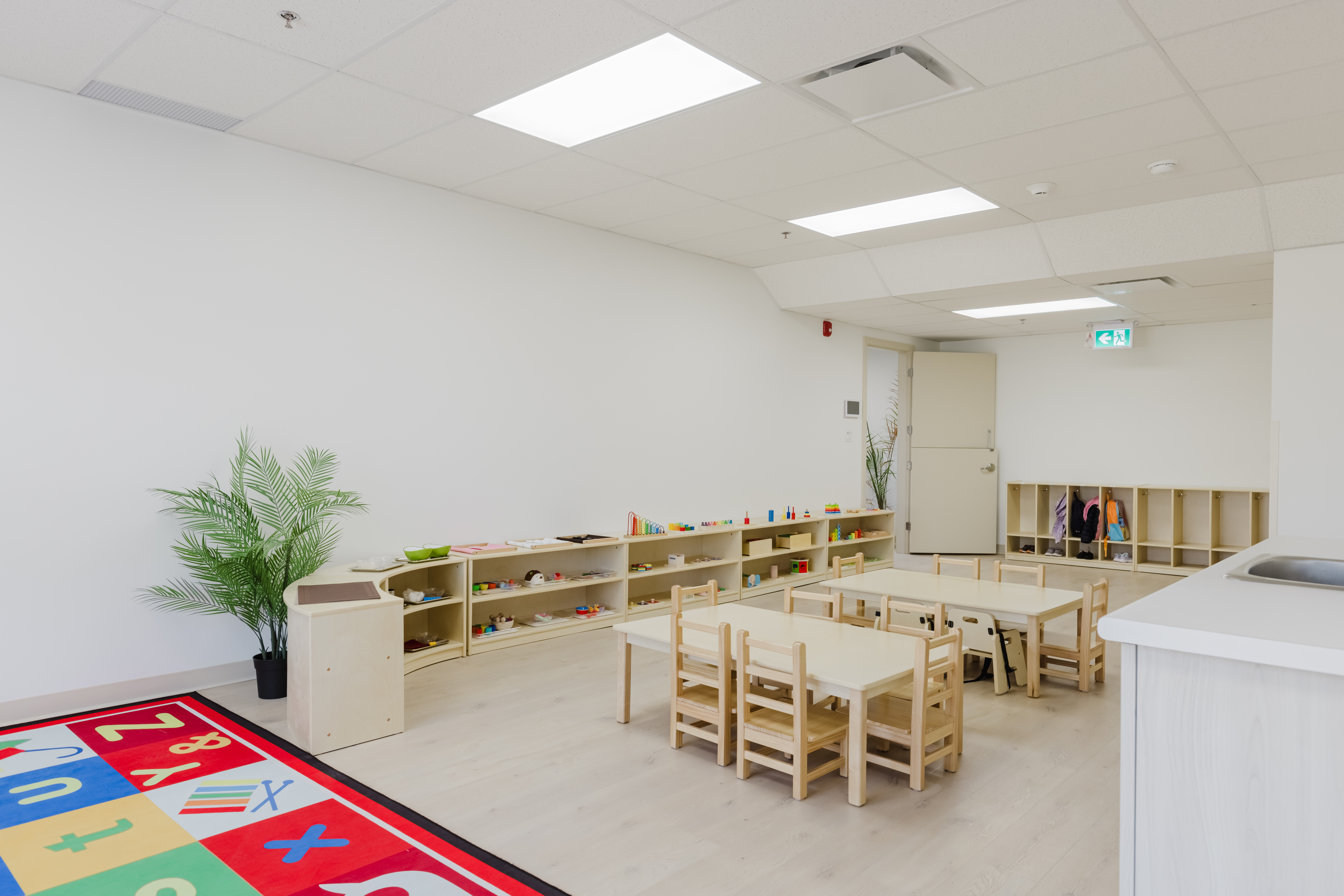 Bright infant program room with cribs and Montessori materials at Kidzville