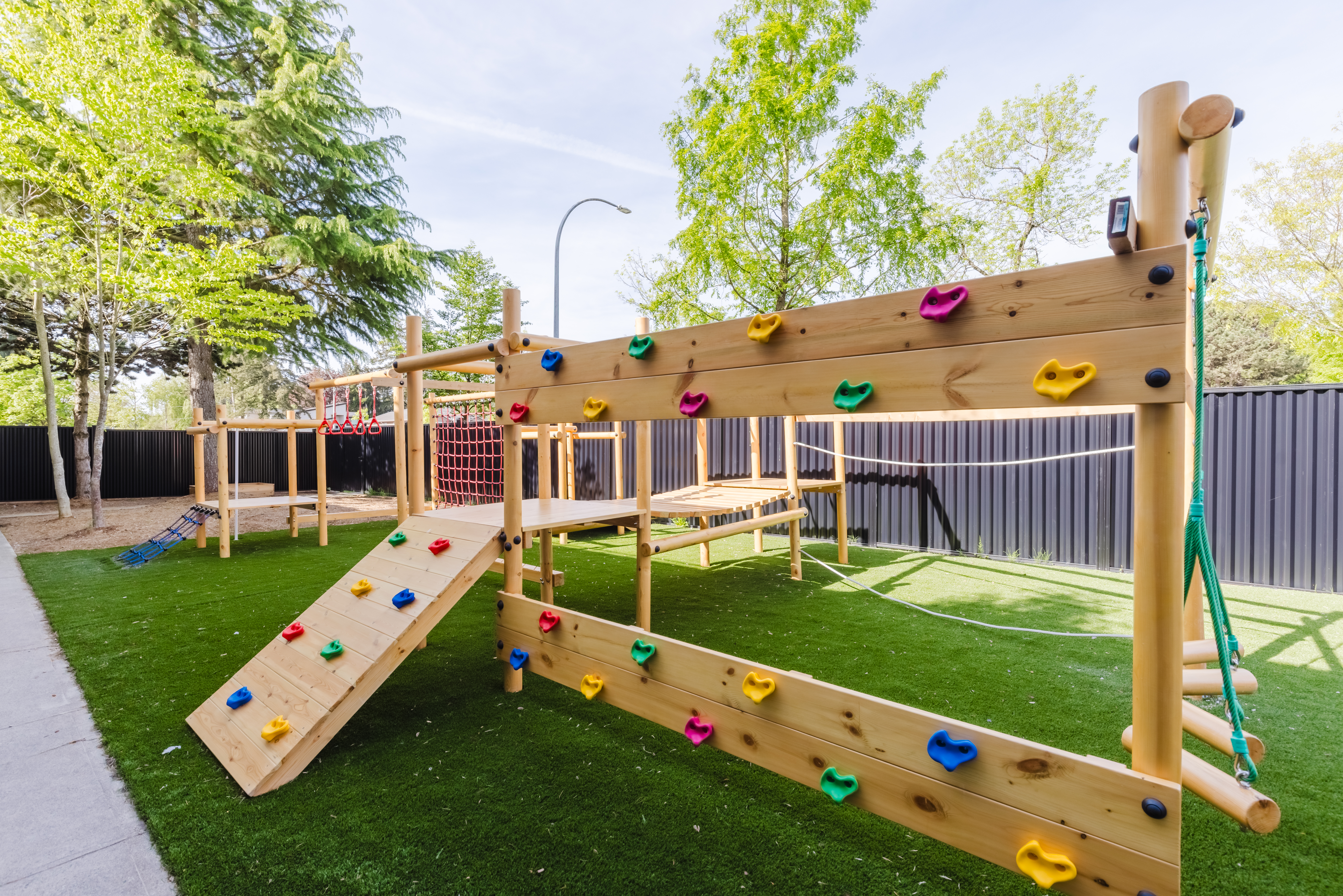 Outdoor wooden climbing frame with rock wall, monkey bars and swings at Kidzville