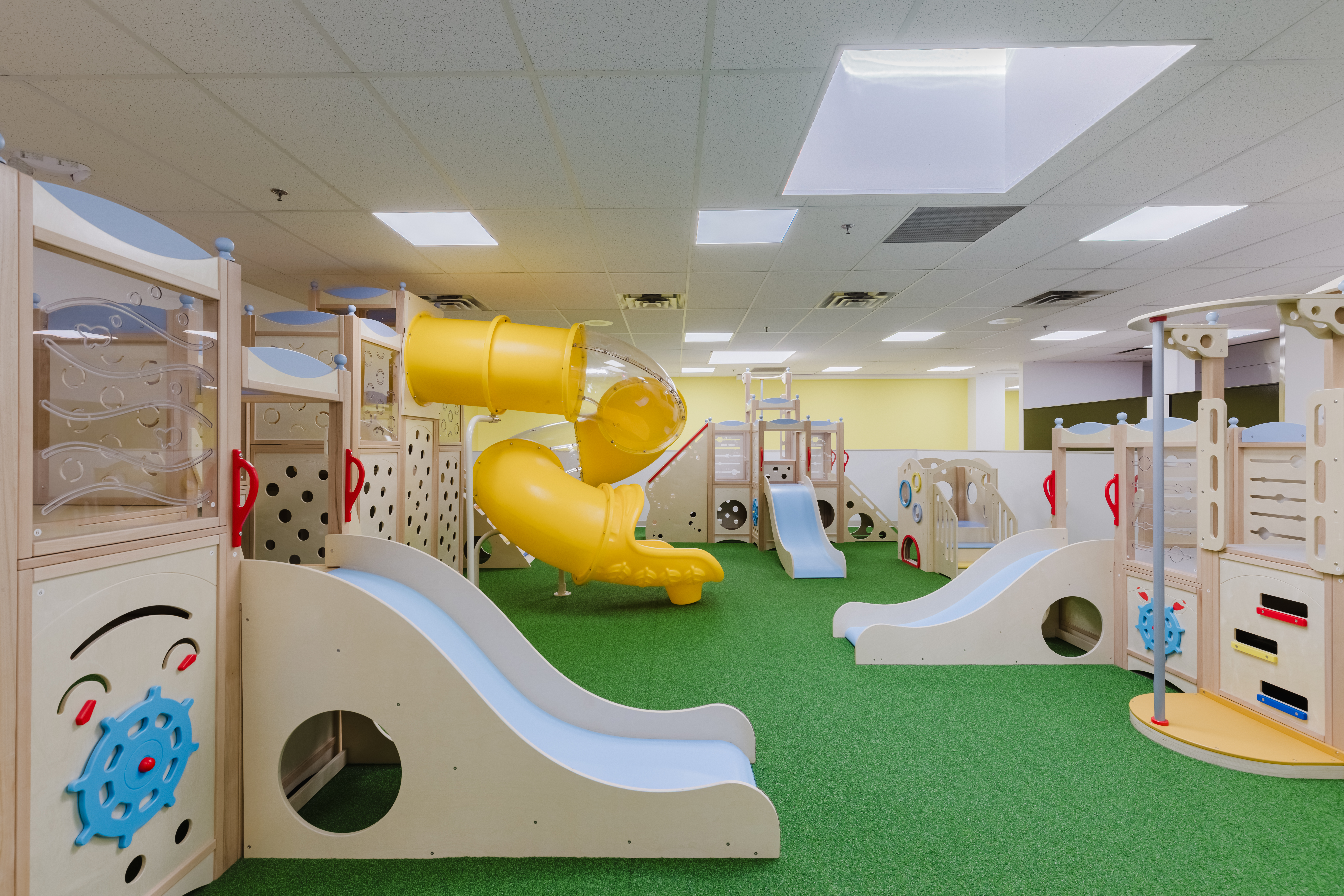 Indoor play gym with yellow tube slide and climbing equipment at Kidzville