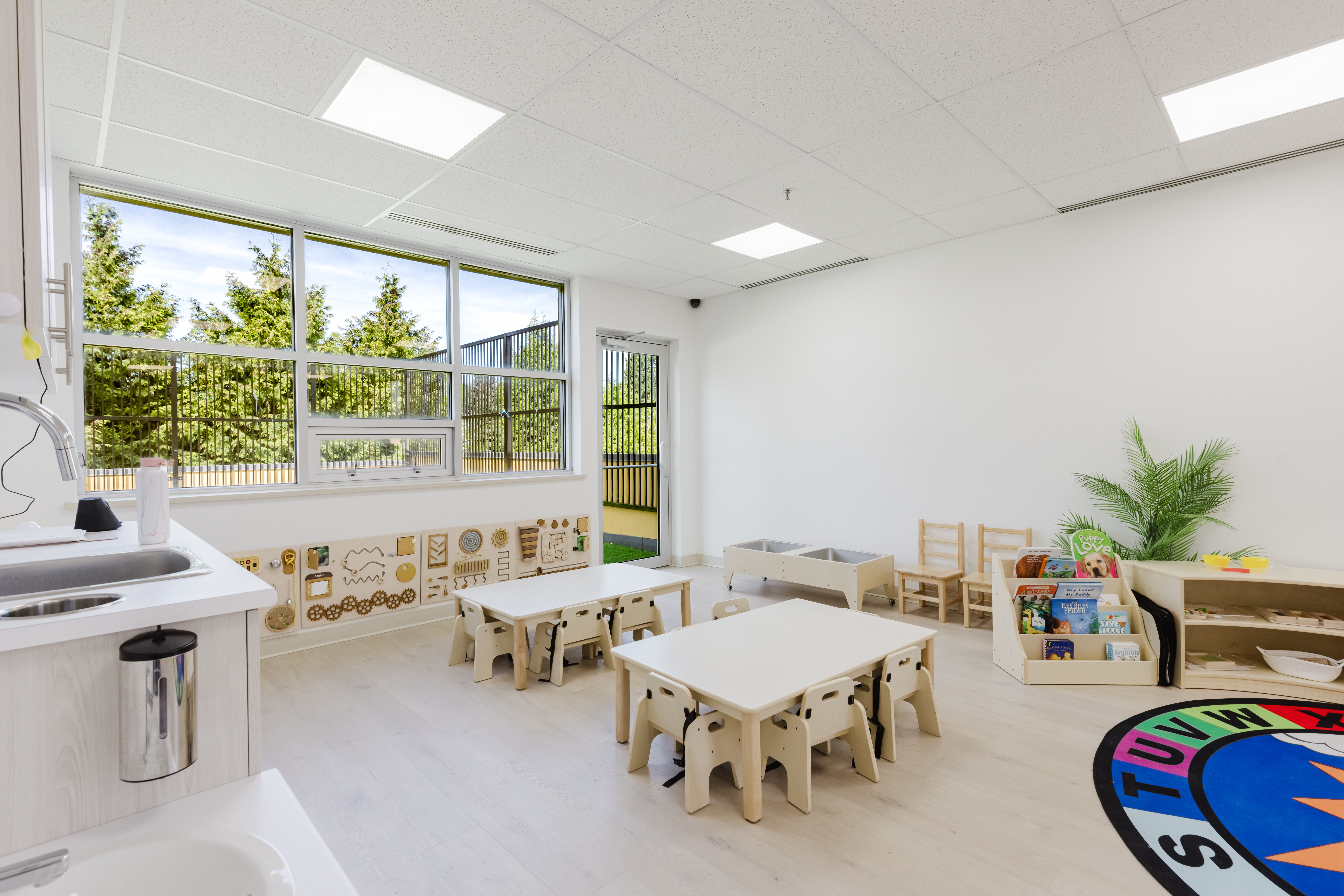 Infant room with insect floor mat and outdoor garden view at Kidzville