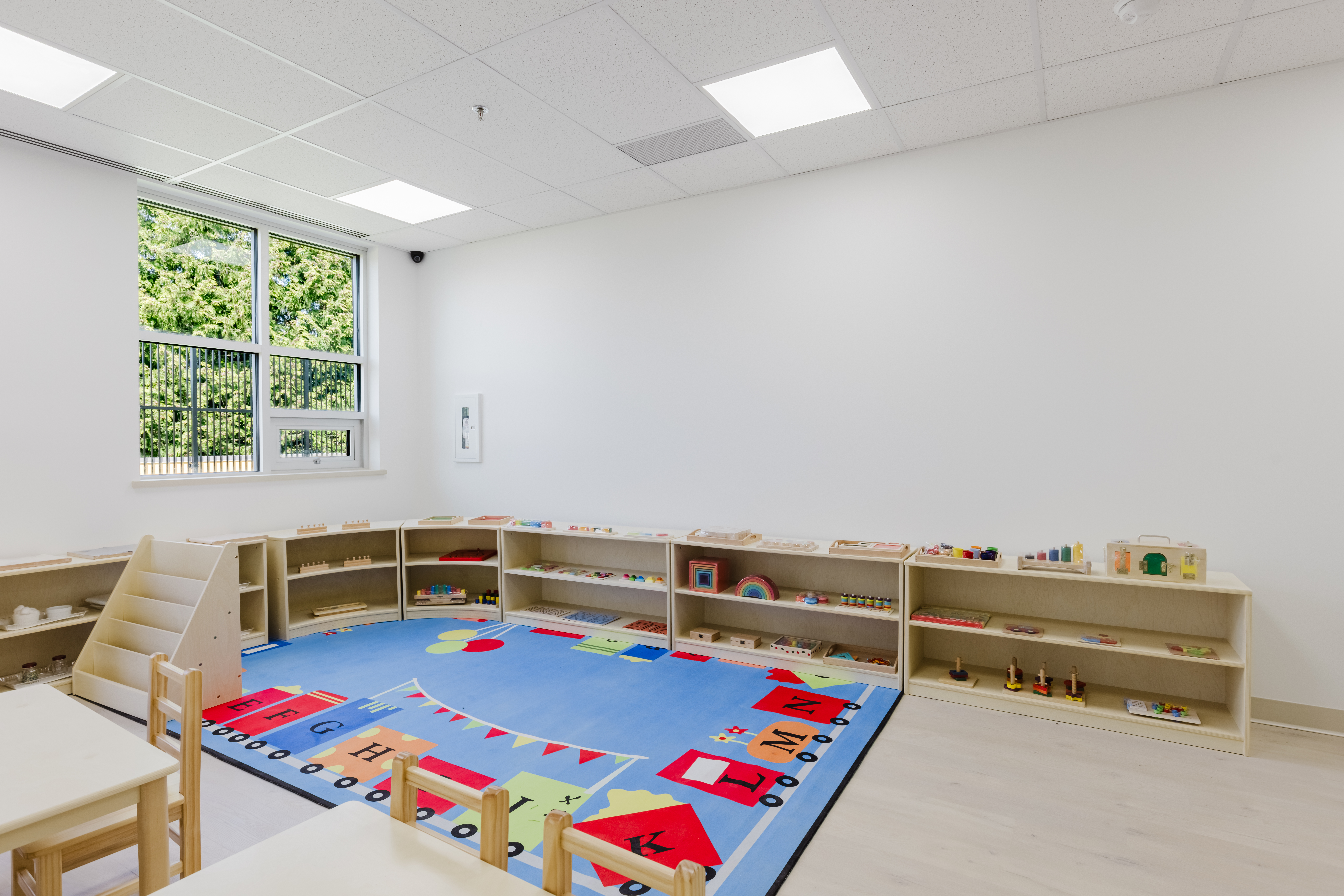 Organised Montessori classroom with curved shelves and work tables at Kidzville
