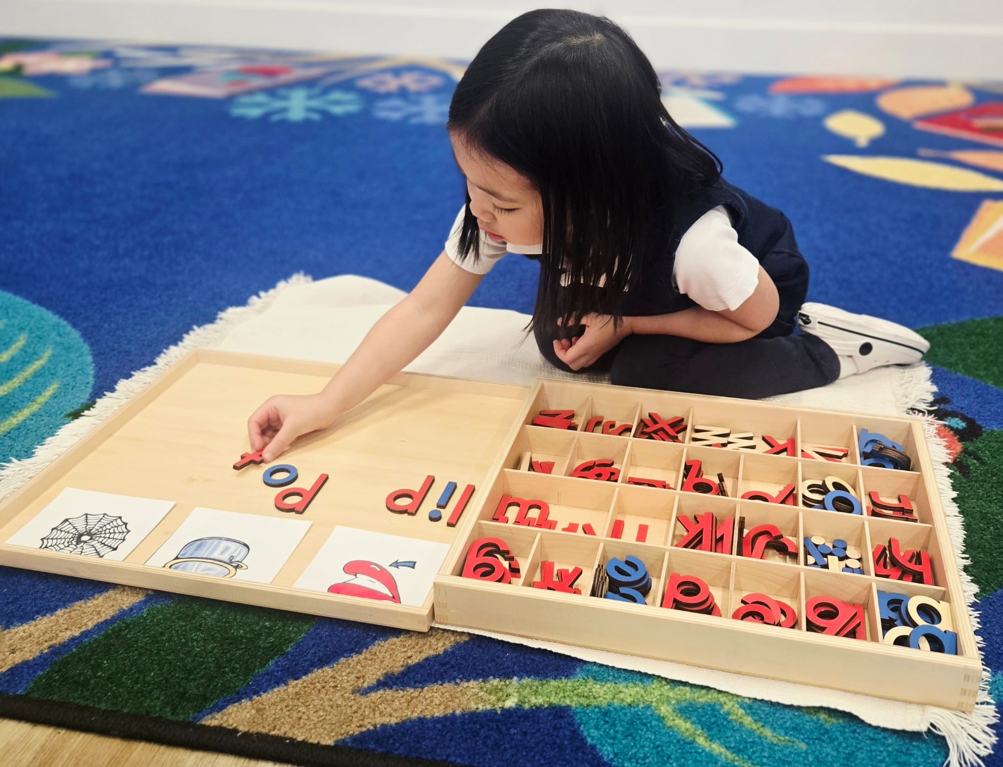 Child building words with the Montessori movable alphabet on a classroom rug