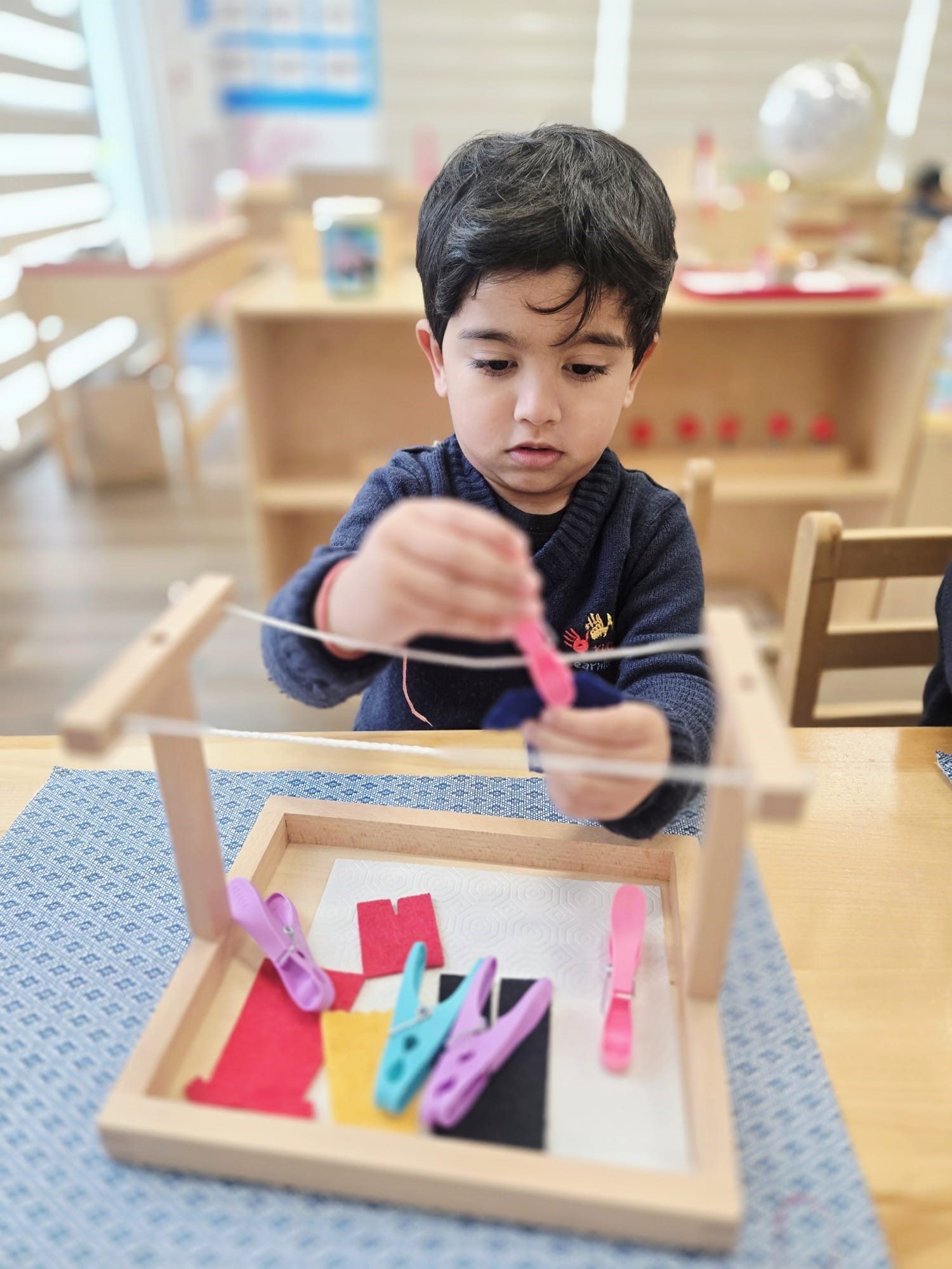 A child focused on a Montessori clothespin activity