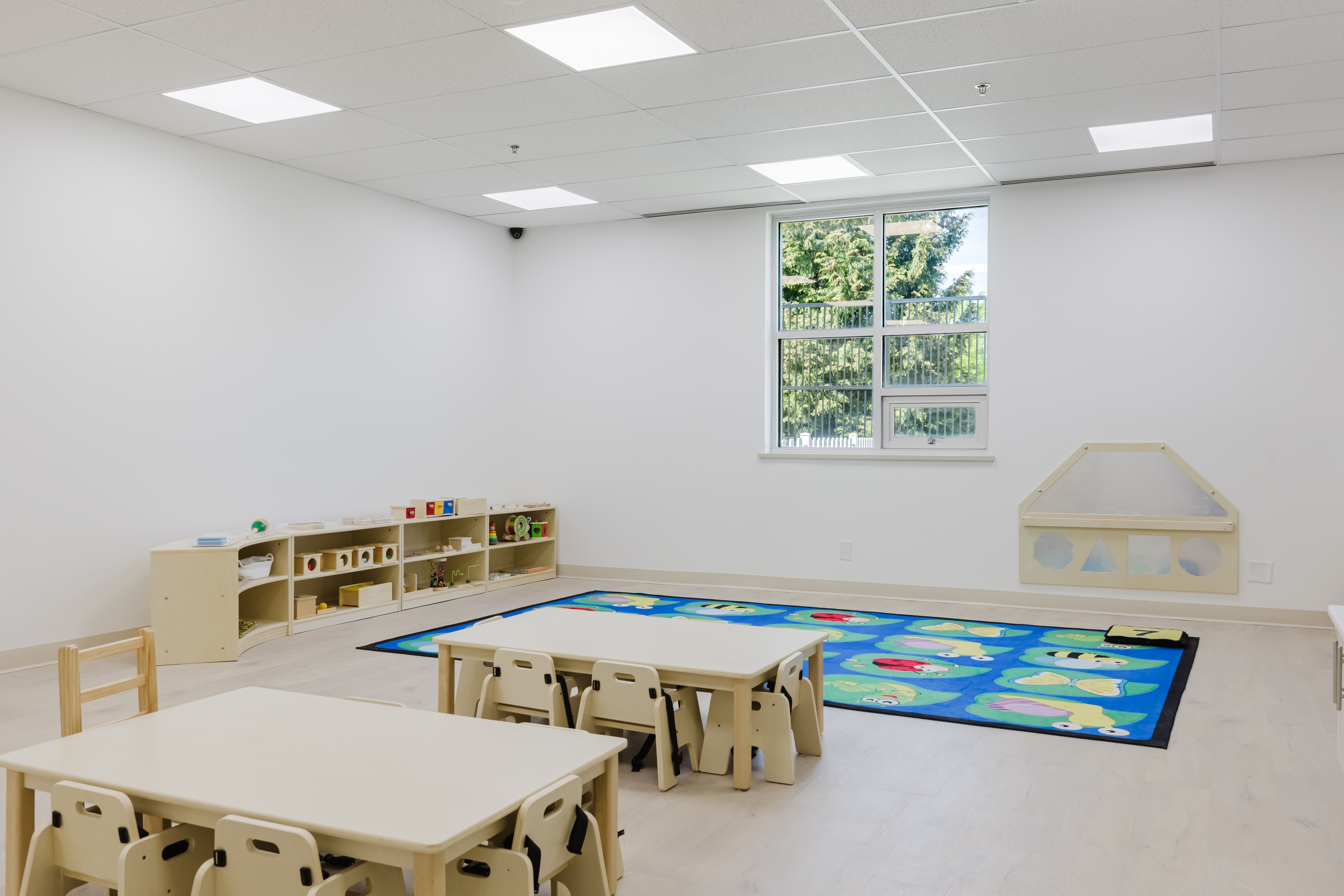 Classroom with alphabet rug and Montessori learning shelves at Kidzville