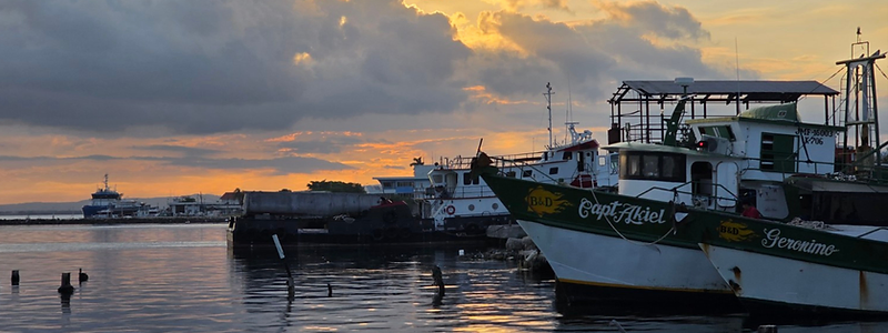 Fishing boats in a harbor at sunset — a destination viewed through the traveler's own map.