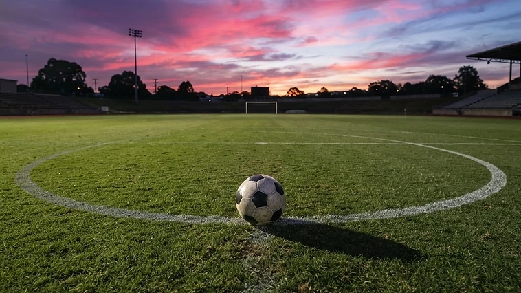 Soccer ball on the center circle of an empty field at dusk