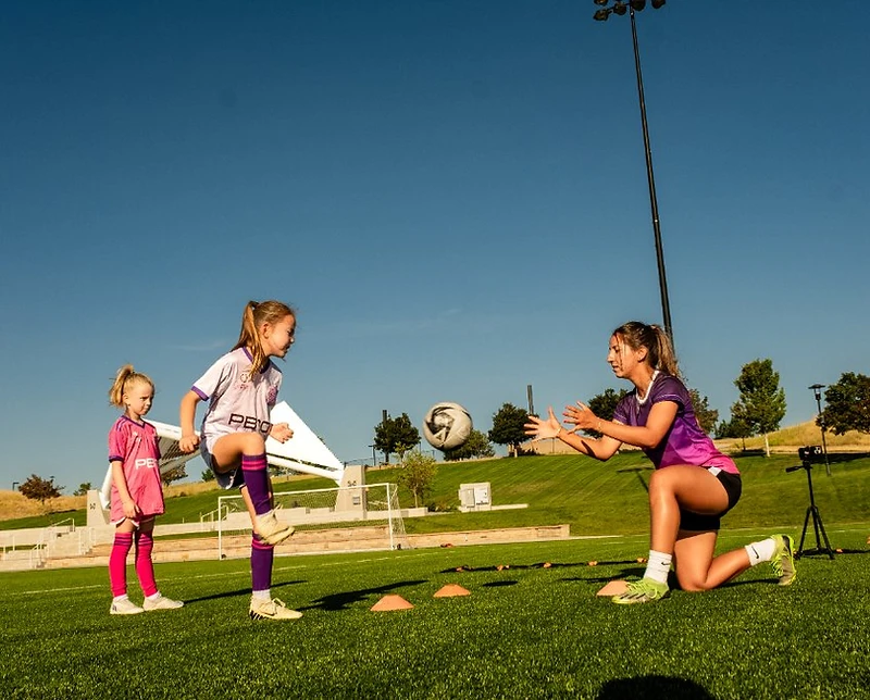 Coach Ana Caroline Egeling actively training homeschooled female soccer players on the field