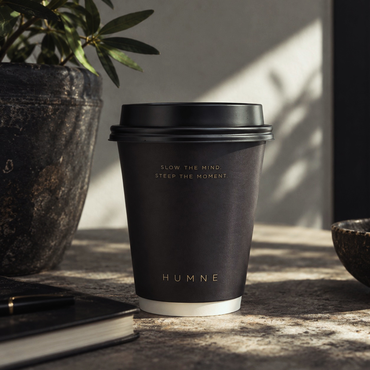 A matte black HUMNE cup resting on a stone surface