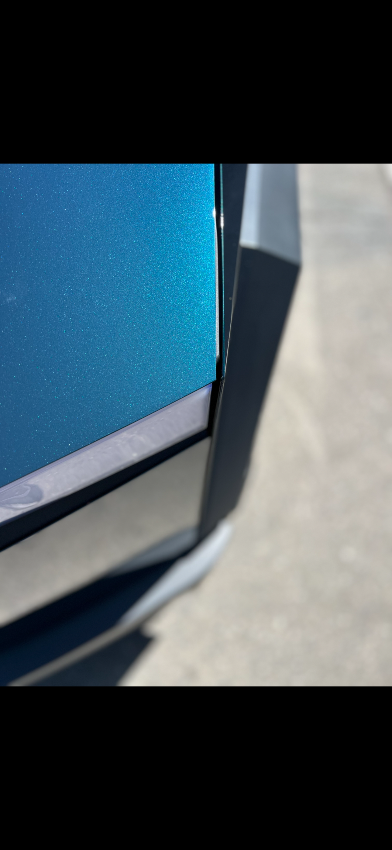 Metallic teal-blue Tesla body panel close-up detail