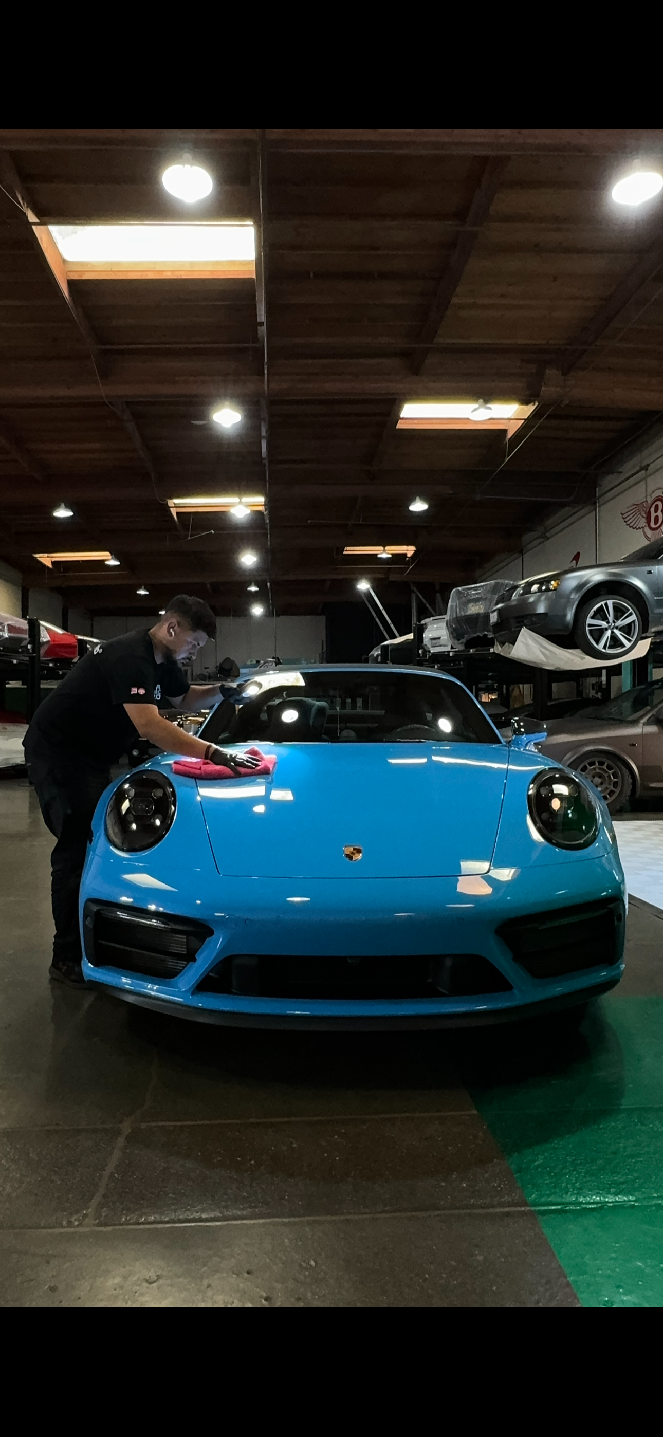 Essence technician inspecting a blue Porsche during ceramic coating application