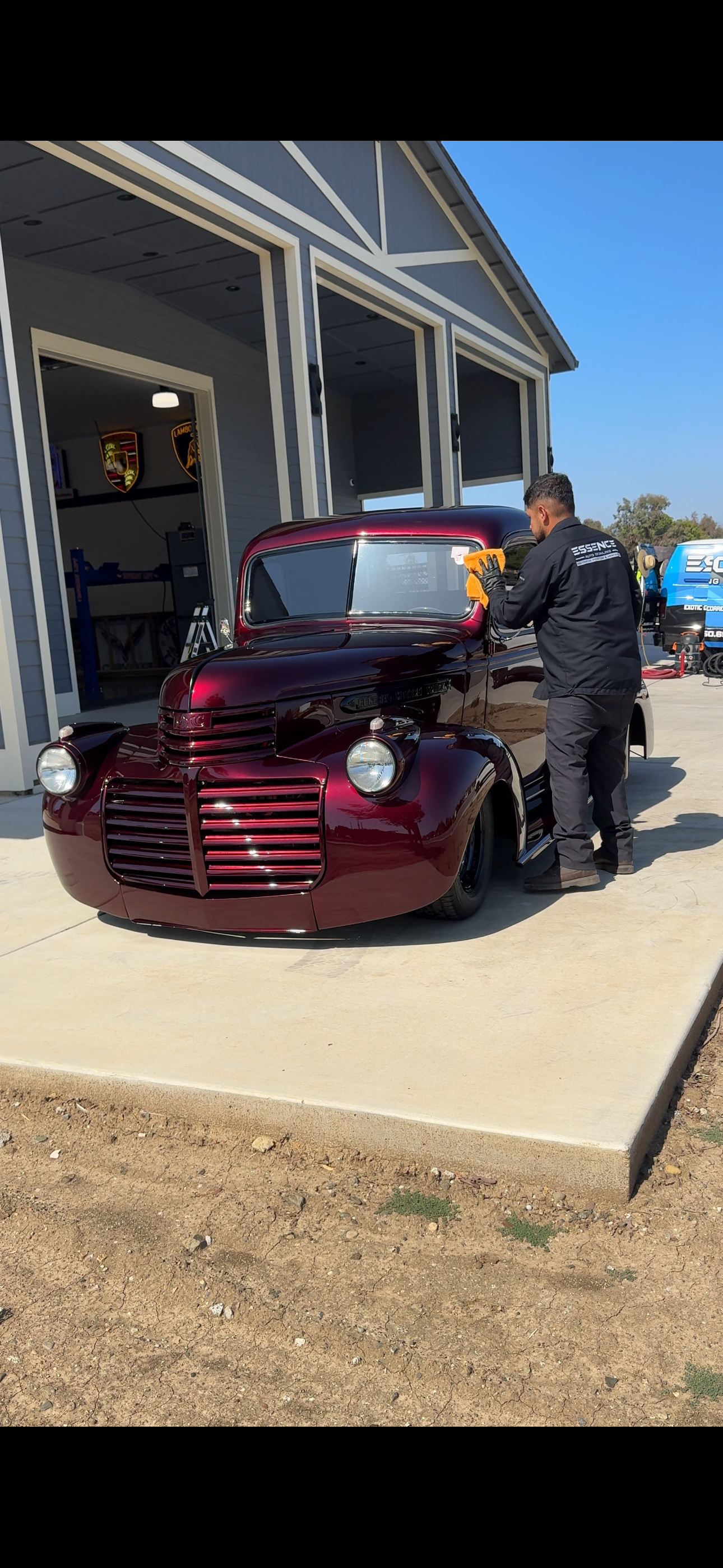 Essence technician wiping the windshield of a classic burgundy pickup truck