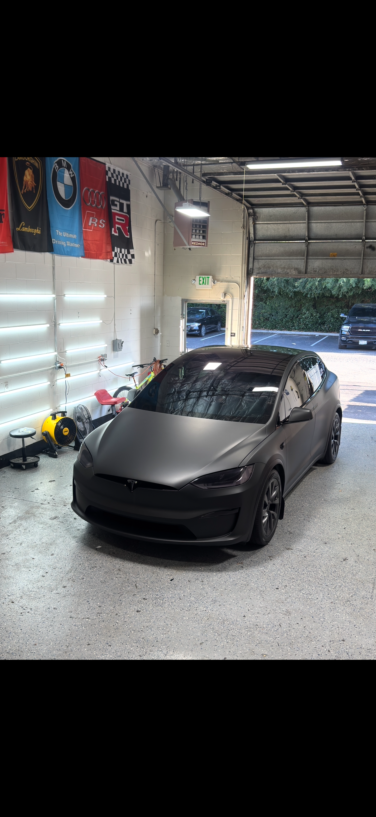 Matte black Tesla Model X front quarter with brand banners