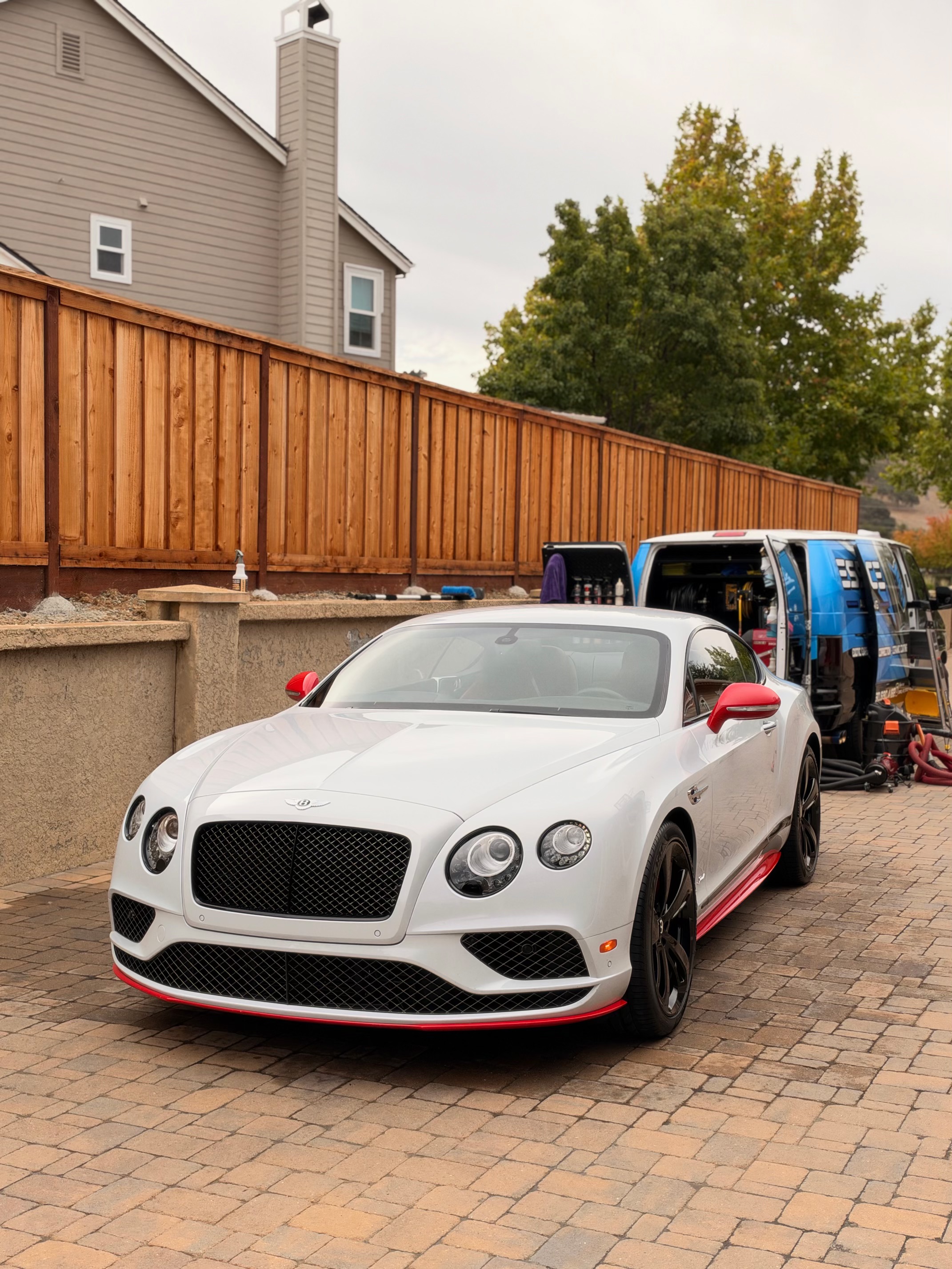 White Bentley Continental GT with red accents on paver driveway