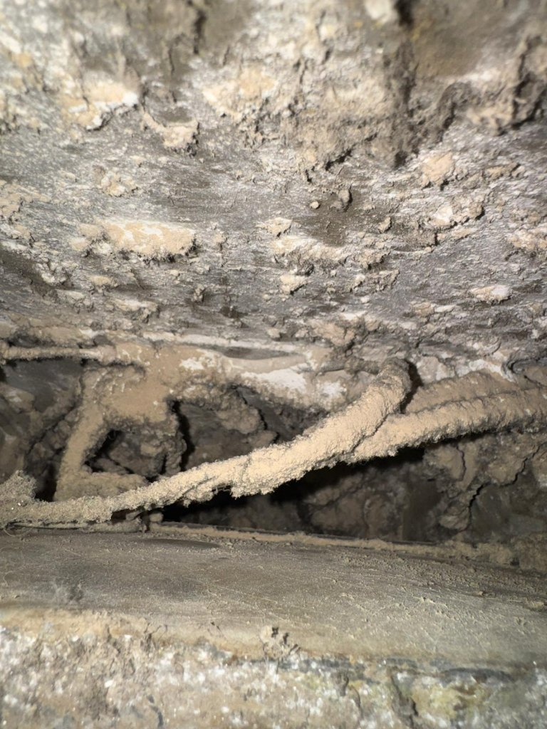 Air duct interior with heavy dust and buildup before cleaning.