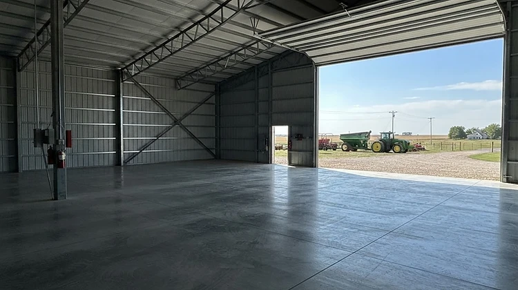 Large fresh concrete floor inside a steel-frame pole barn machine shed