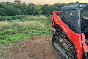 Triple M's Kubota track loader at an overgrown Missouri treeline with freshly cleared ground in front