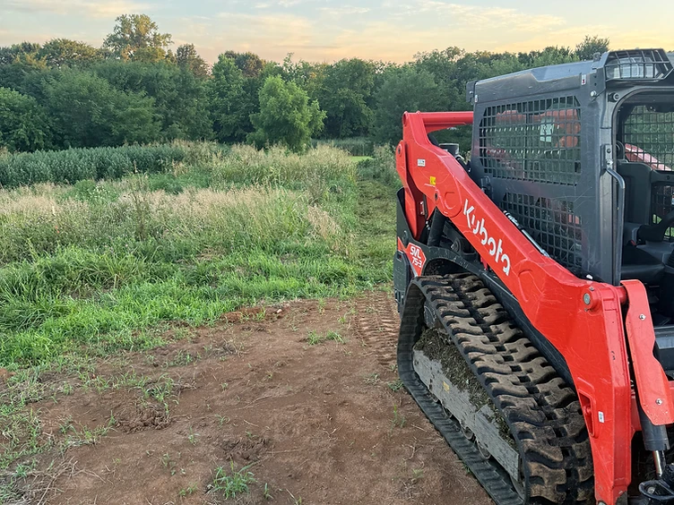 Triple M's Kubota track loader at an overgrown Missouri treeline with freshly cleared ground in front
