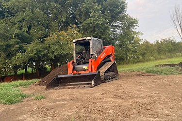 Kubota track loader pushing and leveling fill dirt for a pad on rural Missouri land