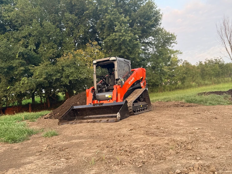 Kubota track loader pushing and leveling fill dirt for a pad on rural Missouri land
