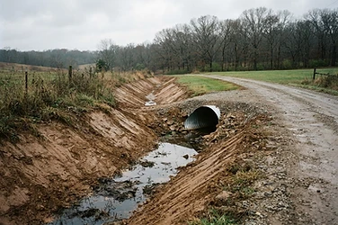 Freshly graded drainage ditch with a culvert pipe along a rural Missouri drive