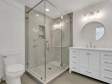 Bathroom with herringbone tile corner shower, glass enclosure, and white single vanity