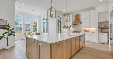 Kitchen with a wood-tone island, a brass-tone range hood, herringbone backsplash, and a breakfast nook by tall windows