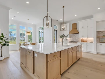 Kitchen with oak island, brass range hood, herringbone backsplash, and breakfast nook by tall windows