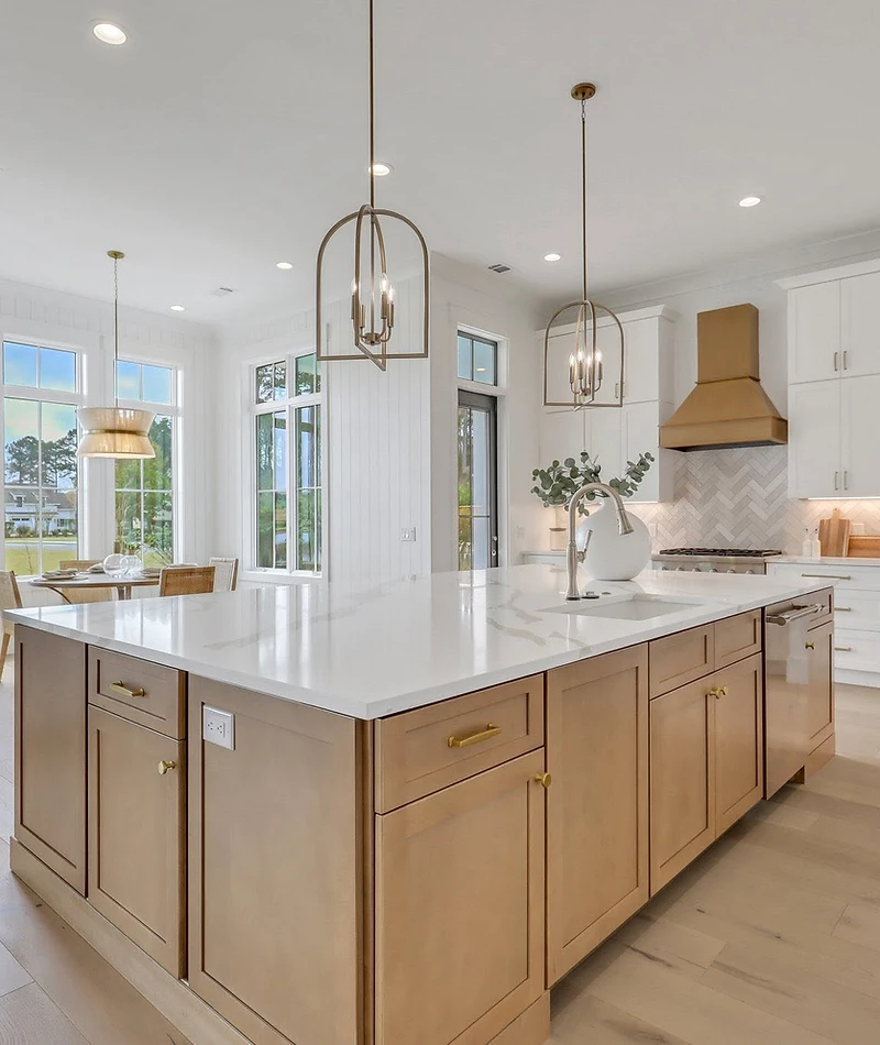 Kitchen with a wood-tone island, a brass-tone range hood, herringbone backsplash, and a breakfast nook by tall windows