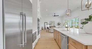 Wide-plank flooring in a light wood tone running from the kitchen into an open living room