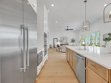 Kitchen run with stainless refrigerator, wall ovens, and white oak flooring into the living room