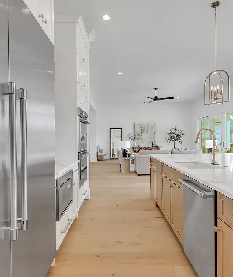Wide-plank flooring in a light wood tone running from the kitchen into an open living room