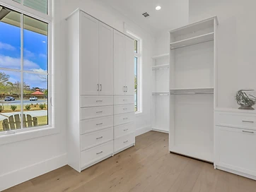 Built-in white closet cabinetry with drawers beside a tall window