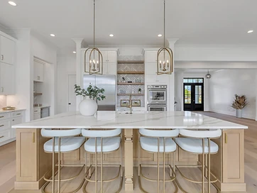 Open kitchen with a large white island top, pendant lights, white cabinets, and a wood-tone island
