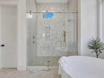 Walk-in shower with marble picket tile, glass slider door, and freestanding tub