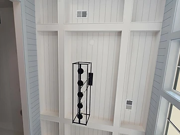 Coffered shiplap ceiling with skylights and a black linear chandelier