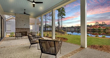 Covered porch with ceiling fans and an outdoor fireplace, overlooking the water