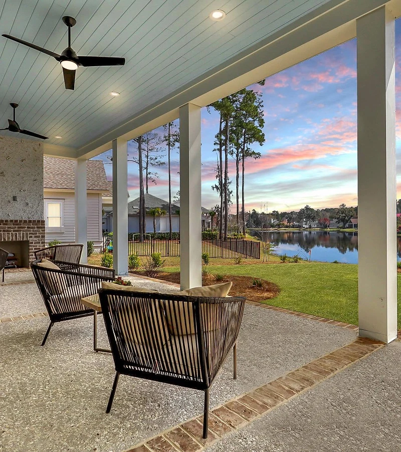 Covered porch with ceiling fans and an outdoor fireplace, overlooking the water