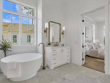 Primary bath with soaking tub under window and open door to the bedroom