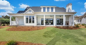 Rear of a white two-story home with a covered porch and an outdoor fireplace