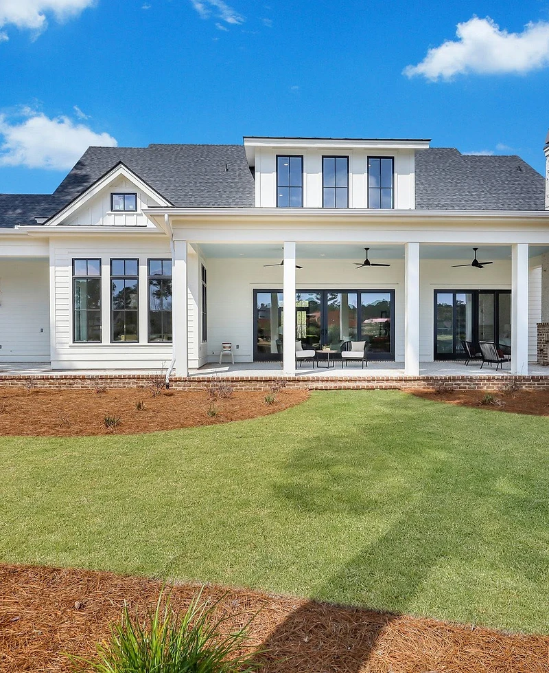 Rear of a white two-story home with a covered porch and an outdoor fireplace