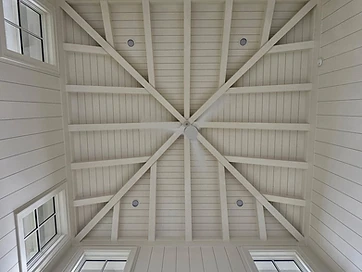 Vaulted shiplap ceiling with crossed white beams and clerestory windows