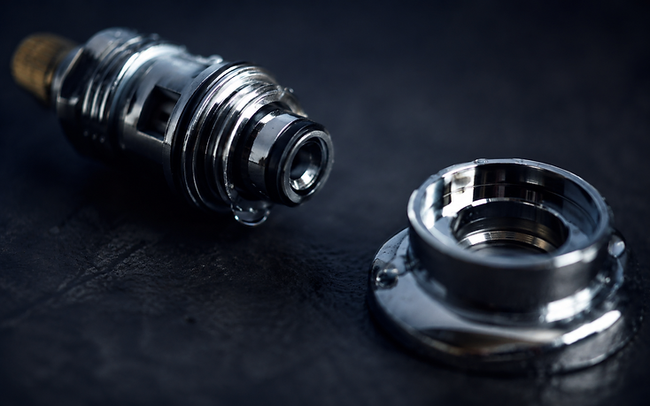 Chrome faucet cartridge and valve seat on a dark surface