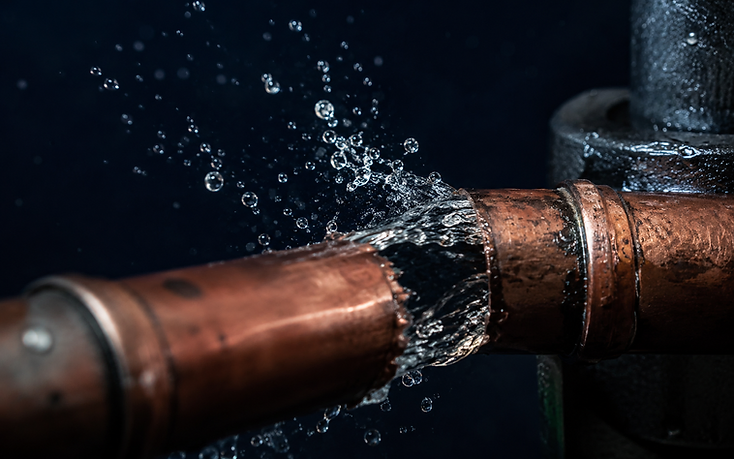 Macro view of a split copper supply pipe spraying pressurized water