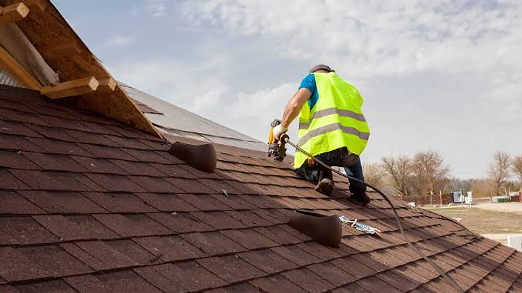 Roofer installing shingles on a residential roof