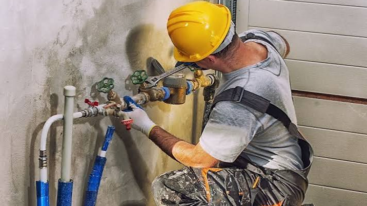 Plumber repairing pipes under a kitchen sink