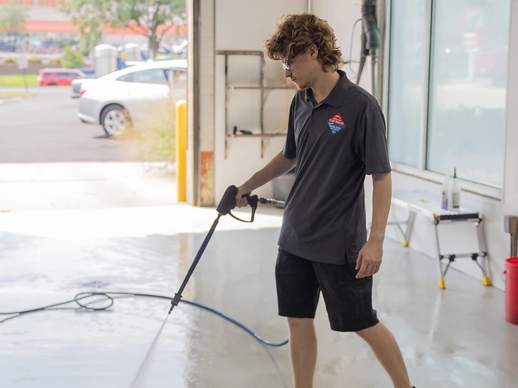 Millennium Auto Wash employee pressure washing the bay