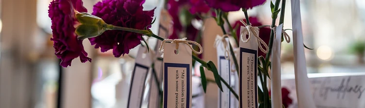 Purple carnations with tags carrying quotes from Maya Angelou and Malala Yousafzai