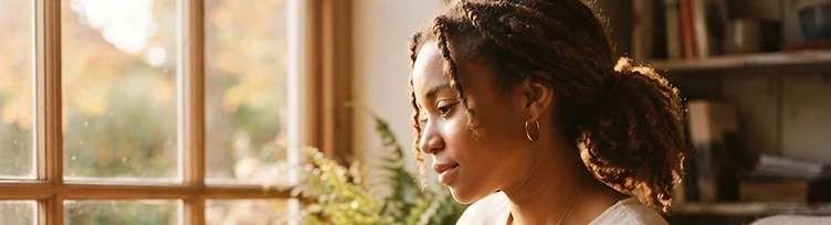 A young African American adult sitting quietly in warm light