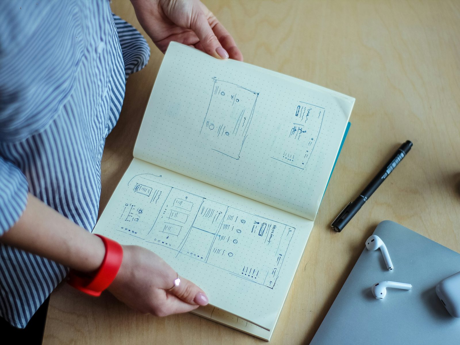 Notebook of sketched app wireframes on a wooden desk