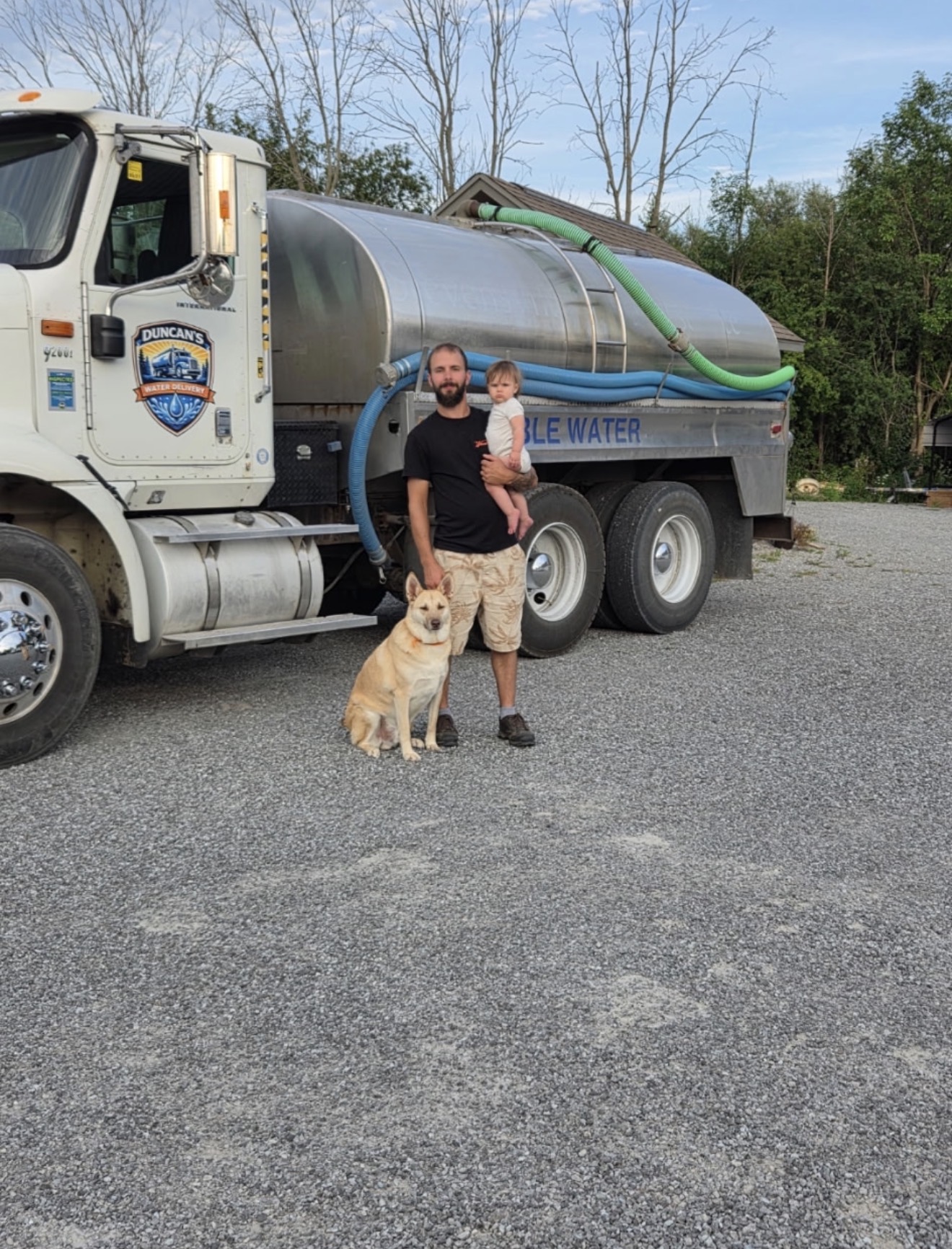 Owner Nic Duncan holding his child with the family dog beside the Duncan's Water Delivery truck